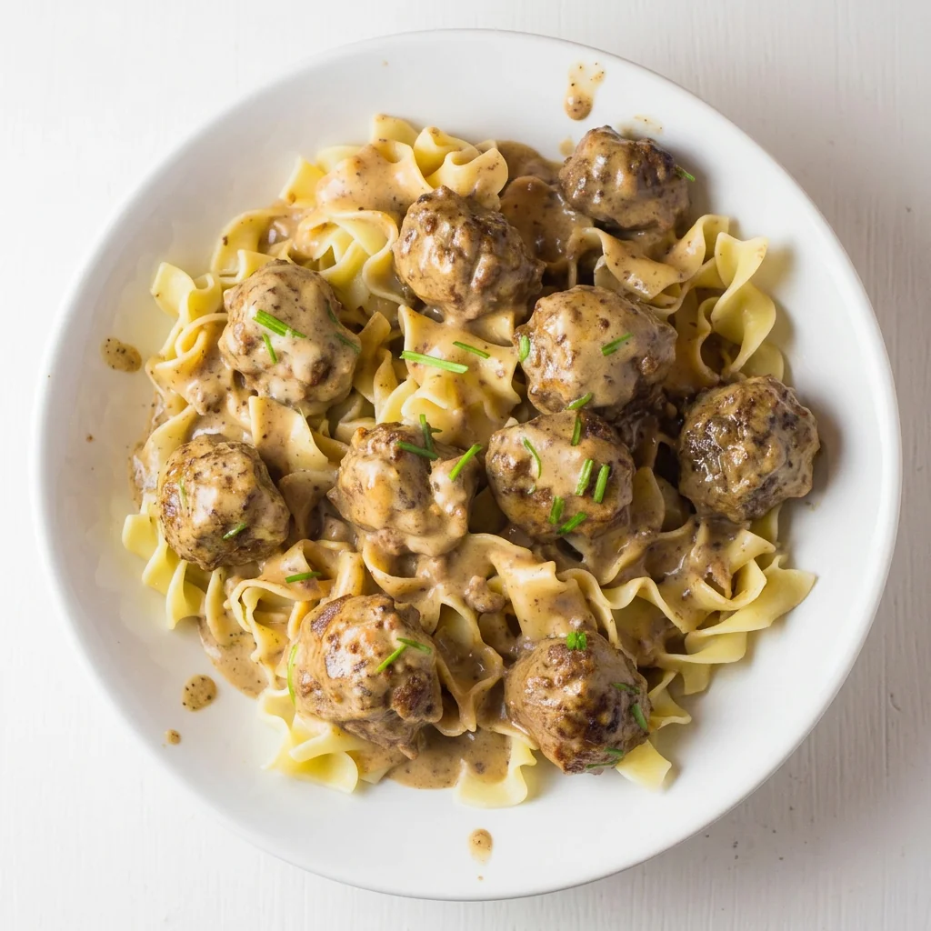 Overhead view of Swedish meatballs and egg noodles in creamy sauce in a white bowl